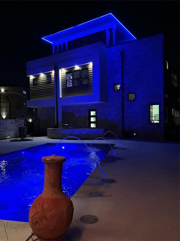 pool at night featuring pool water feature