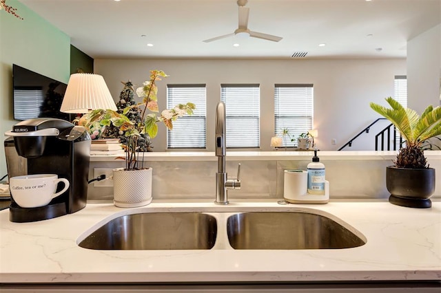 details with ceiling fan, light stone counters, and sink