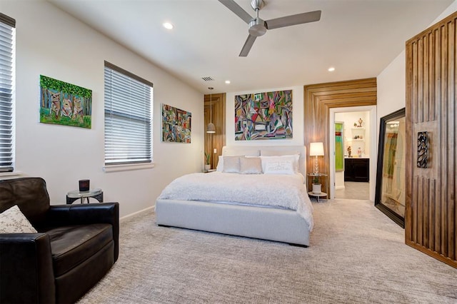 bedroom featuring light carpet, ensuite bathroom, and ceiling fan