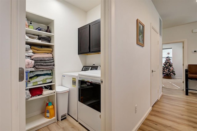 clothes washing area with cabinets, independent washer and dryer, and light wood-type flooring