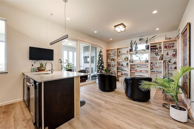 kitchen with sink, beverage cooler, hanging light fixtures, light hardwood / wood-style flooring, and kitchen peninsula