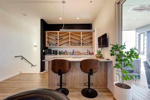 bar featuring decorative light fixtures and light hardwood / wood-style flooring