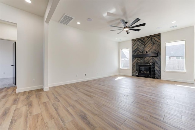 unfurnished living room featuring ceiling fan, a large fireplace, and light hardwood / wood-style flooring