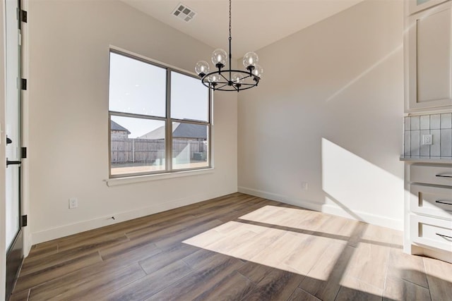 unfurnished dining area with an inviting chandelier and dark wood-type flooring