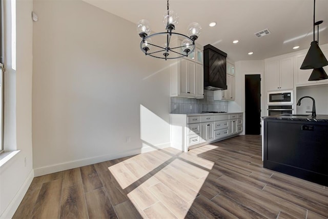 kitchen with white cabinets, sink, built in microwave, a notable chandelier, and dark hardwood / wood-style flooring