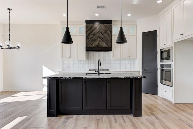 kitchen with light hardwood / wood-style floors, white cabinetry, stainless steel appliances, and hanging light fixtures