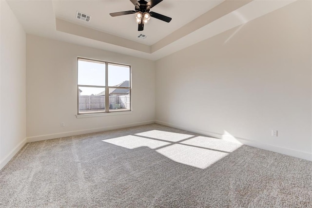 spare room with a tray ceiling, ceiling fan, and carpet floors