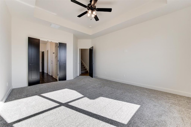 bedroom featuring ceiling fan, dark carpet, and a tray ceiling