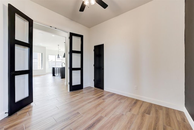 empty room featuring ceiling fan, french doors, and light hardwood / wood-style flooring