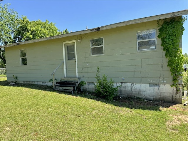 back of house with crawl space, entry steps, and a lawn