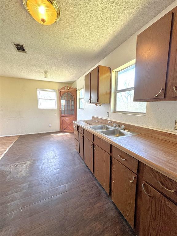 kitchen with a textured ceiling, a sink, dark wood finished floors, and light countertops
