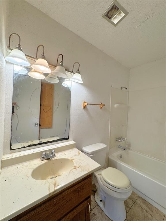 full bathroom featuring a textured ceiling, vanity, toilet, shower / washtub combination, and tile patterned flooring