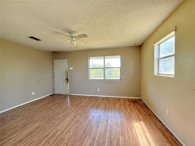 spare room with wood finished floors, a textured ceiling, ceiling fan, and baseboards