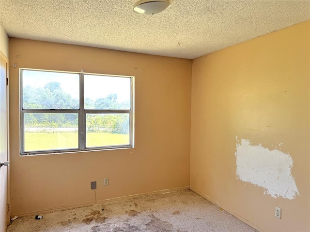 carpeted spare room featuring baseboards and a textured ceiling