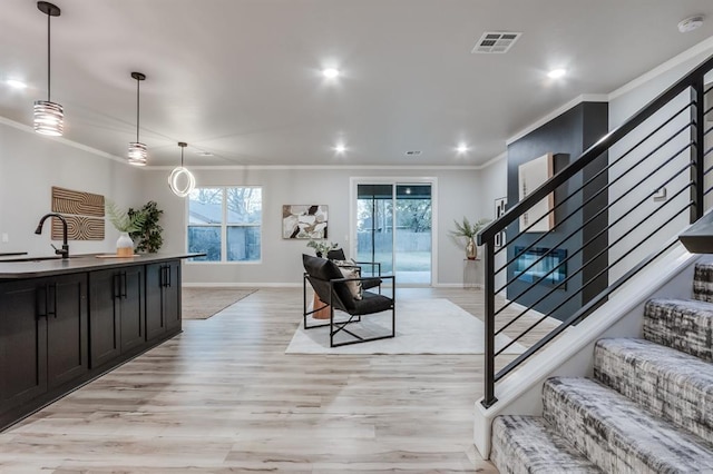 living room featuring light hardwood / wood-style floors, ornamental molding, and sink