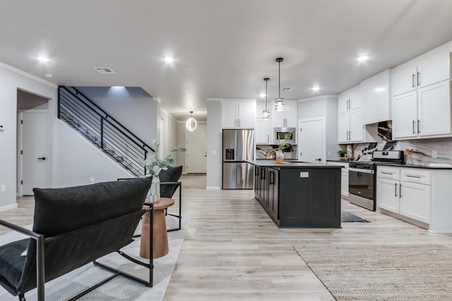 kitchen with white cabinets, a kitchen island, backsplash, and appliances with stainless steel finishes