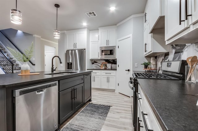 kitchen featuring sink, stainless steel appliances, tasteful backsplash, decorative light fixtures, and white cabinets