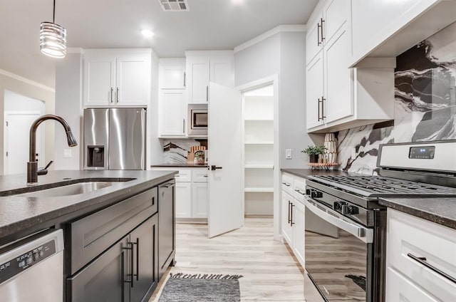 kitchen featuring sink, decorative backsplash, appliances with stainless steel finishes, decorative light fixtures, and white cabinetry