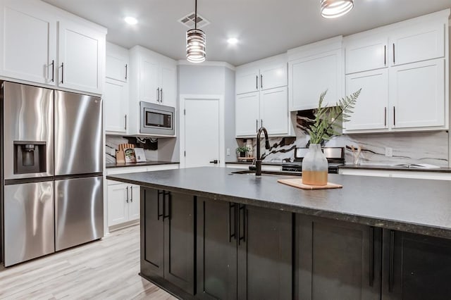 kitchen with decorative backsplash, white cabinetry, appliances with stainless steel finishes, and light hardwood / wood-style flooring