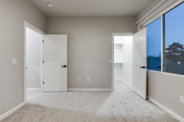 unfurnished bedroom with light carpet and a spacious closet