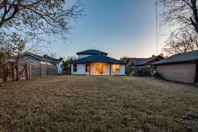 back house at dusk featuring a yard