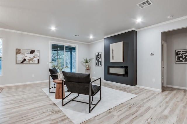 dining space with crown molding, light hardwood / wood-style flooring, and a large fireplace