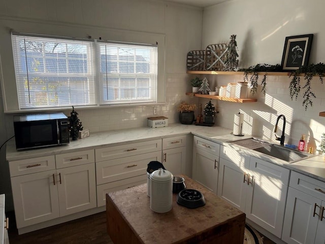 kitchen with tasteful backsplash, sink, and white cabinets