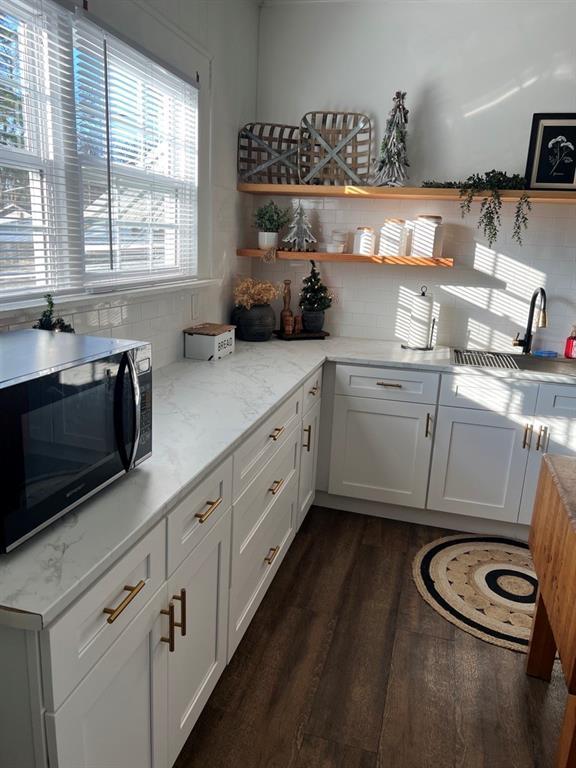 kitchen featuring light stone countertops, decorative backsplash, dark hardwood / wood-style flooring, and white cabinetry