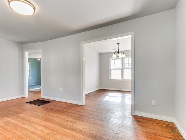 spare room featuring light hardwood / wood-style flooring and a notable chandelier