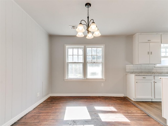 unfurnished dining area featuring wood-type flooring and a notable chandelier