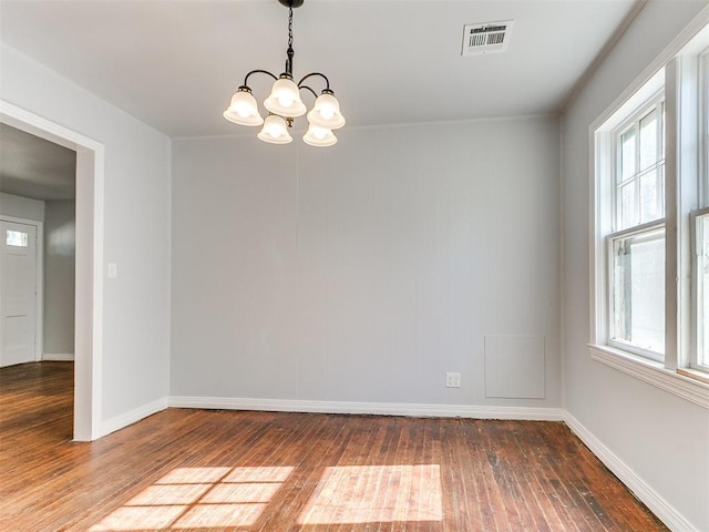 spare room featuring dark wood-type flooring and a notable chandelier