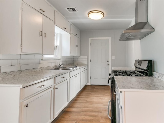 kitchen with white cabinetry, sink, wall chimney exhaust hood, and range with gas cooktop