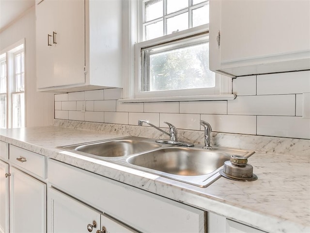 kitchen featuring white cabinets, decorative backsplash, and sink