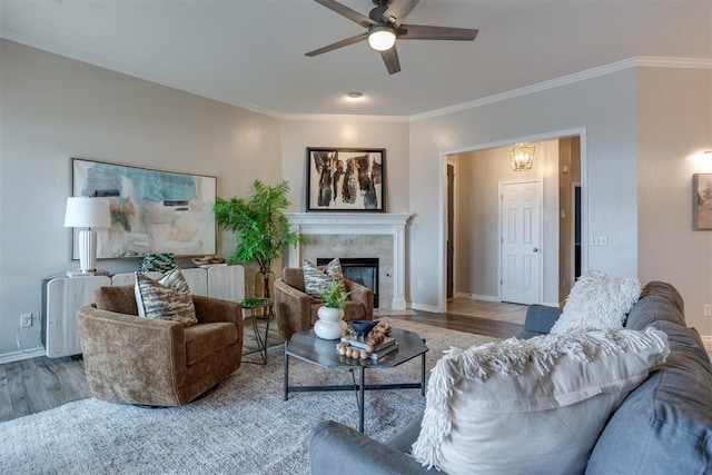 living room with crown molding, ceiling fan, a high end fireplace, and light wood-type flooring