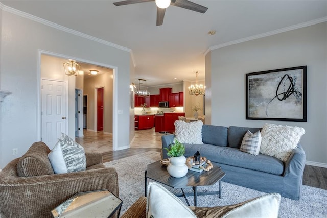 living room with ornamental molding, ceiling fan with notable chandelier, and light hardwood / wood-style flooring