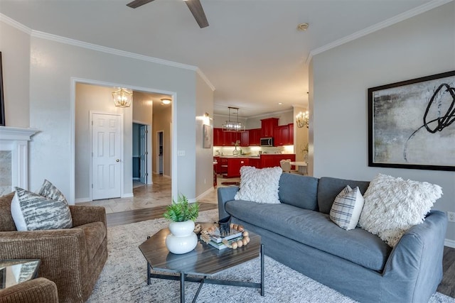 living room with ceiling fan with notable chandelier, light hardwood / wood-style flooring, and ornamental molding