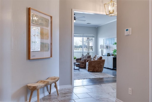 hallway with an inviting chandelier and ornamental molding