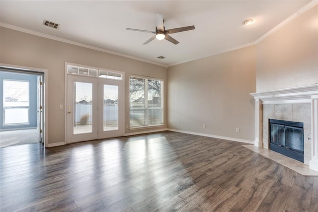 unfurnished living room with a tiled fireplace, crown molding, dark hardwood / wood-style flooring, and ceiling fan