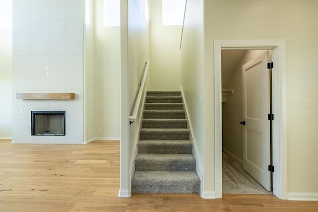 stairs with hardwood / wood-style floors and a large fireplace