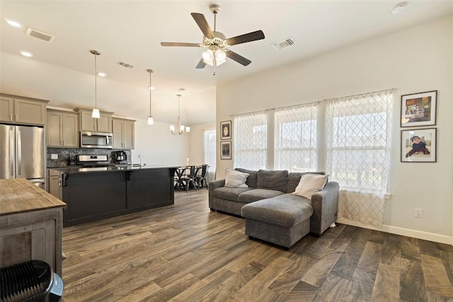 living room with dark hardwood / wood-style flooring, ceiling fan with notable chandelier, and sink