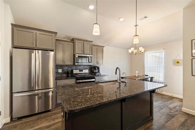 kitchen featuring pendant lighting, sink, a notable chandelier, dark hardwood / wood-style flooring, and stainless steel appliances