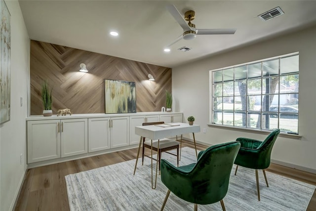 office with ceiling fan, wood walls, and light wood-type flooring