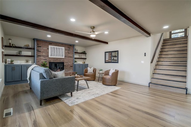 living room with ceiling fan, light wood-type flooring, and a brick fireplace