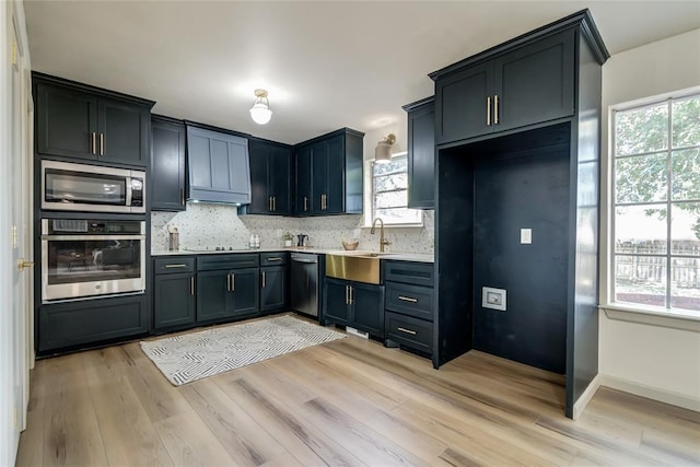 kitchen with appliances with stainless steel finishes, light hardwood / wood-style floors, and a wealth of natural light