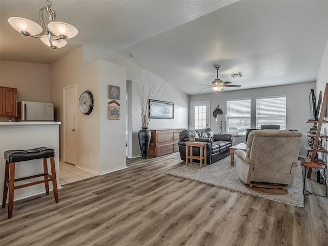 living room featuring ceiling fan with notable chandelier, light hardwood / wood-style floors, and lofted ceiling