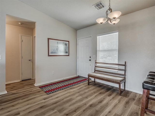 foyer with hardwood / wood-style floors, vaulted ceiling, and a notable chandelier