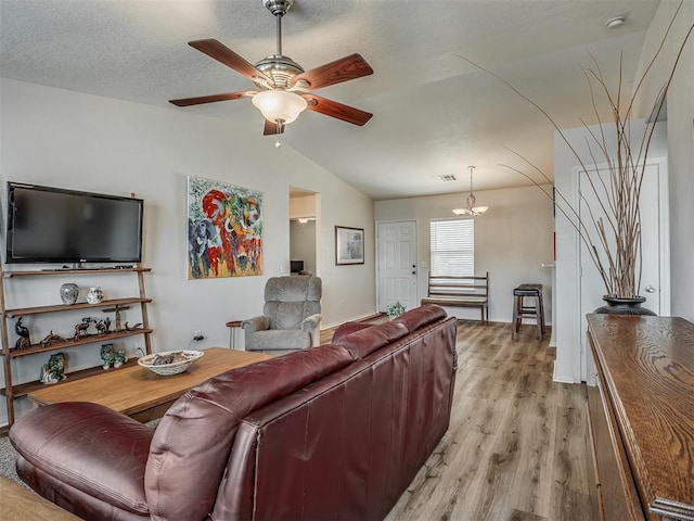 living room featuring light hardwood / wood-style flooring, ceiling fan with notable chandelier, and lofted ceiling