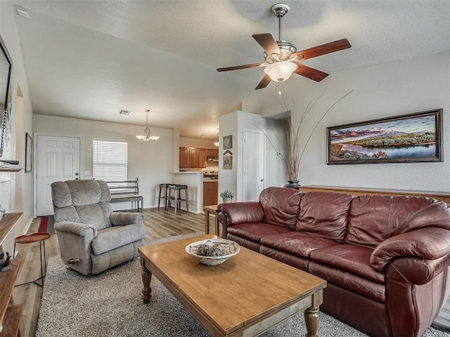 living room with light colored carpet and ceiling fan with notable chandelier