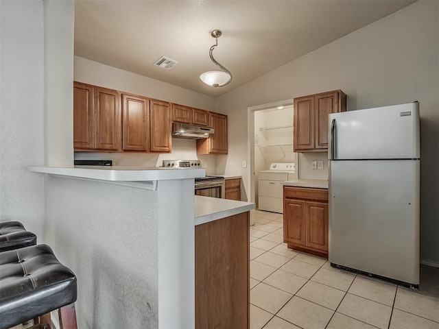 kitchen with white refrigerator, electric stove, vaulted ceiling, a kitchen bar, and washer / clothes dryer