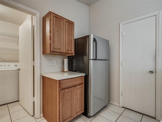 kitchen featuring washer / clothes dryer, stainless steel fridge, and light tile patterned flooring